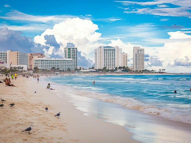 People on cancun beach clouds in the background behind the buldings