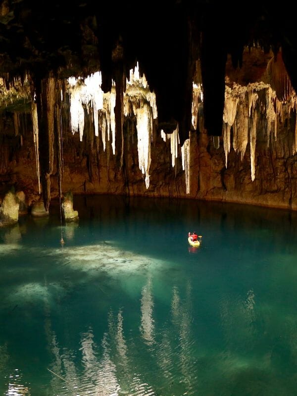 men canoing in a subterranean river with stalagtite