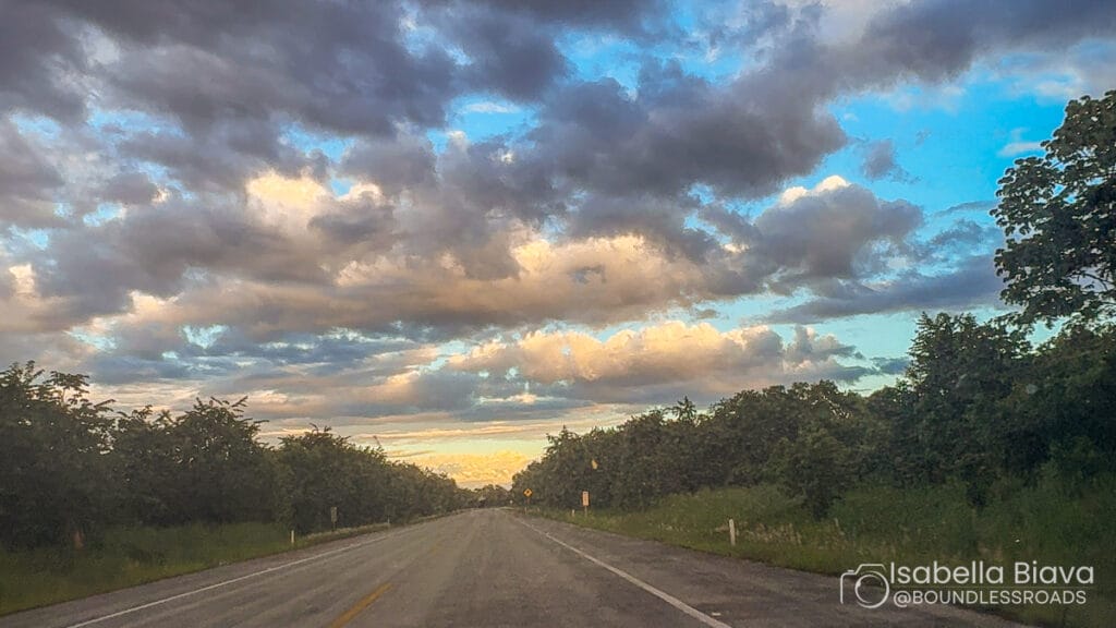 Scenic road under dramatic cloudy sky at sunset.