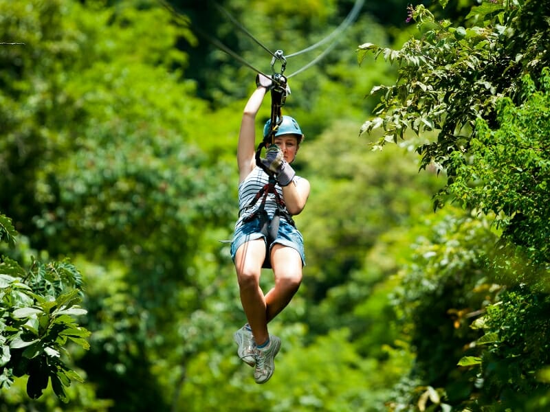 woman ziplining through the forest