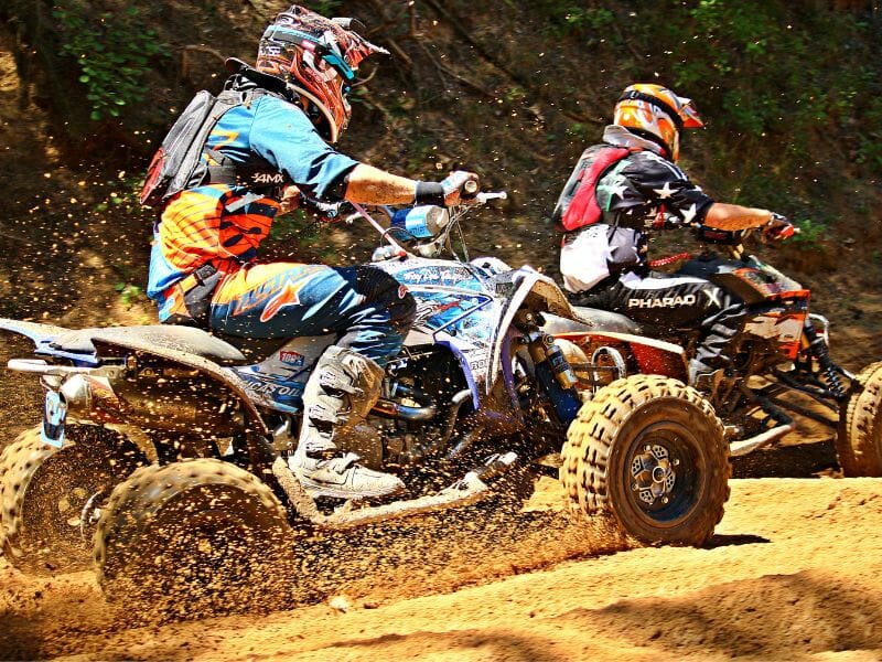 Two rider of ATV in blue and red gears racing.