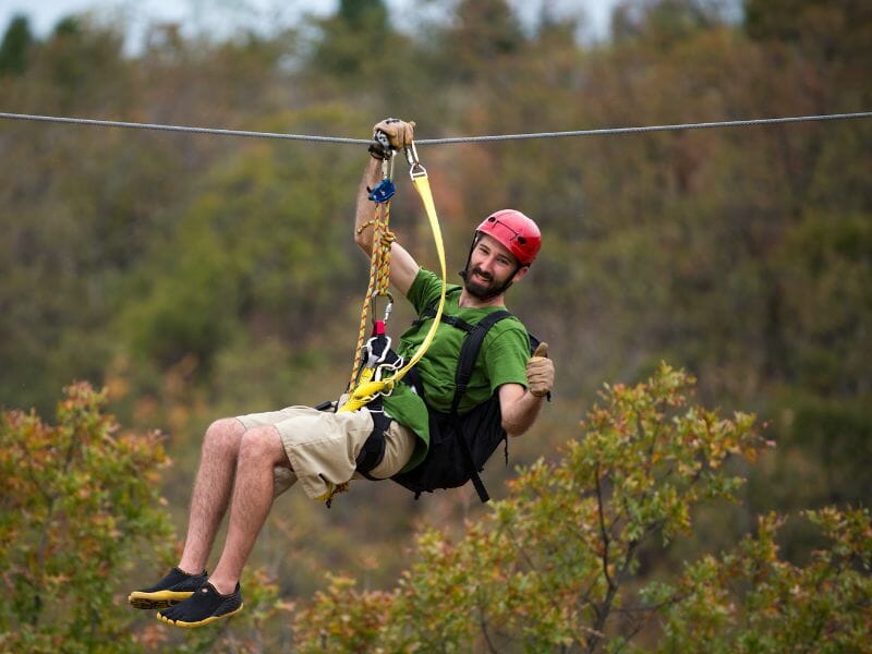 A man in a green shirt is ziplining on one of the best ATV tours in Cancun.