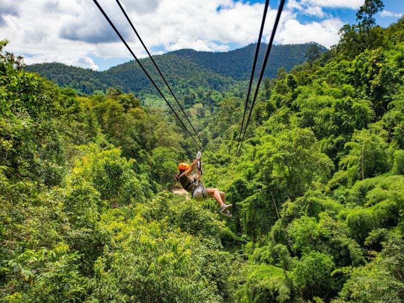 A woman in an orange helmet going down on a zipline in Cancun.