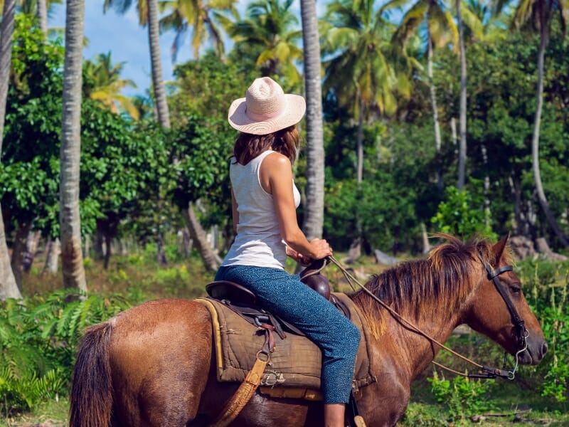 Horseback Riding in Cancun: The Best 7 Tours to Join in 2023 - woman riding a horse through a tropical forest