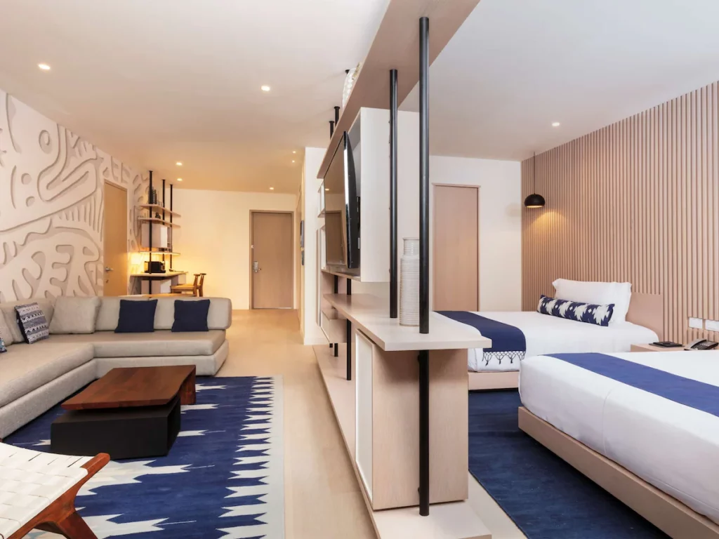 Room with two double beds on the right and on the left a large couch