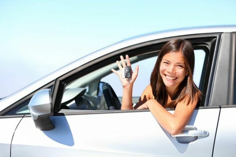 Girl with car keys looking from the car window