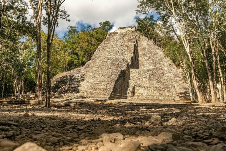 Nohoch Mul Pyramid surrounded by trees on a sunny day.