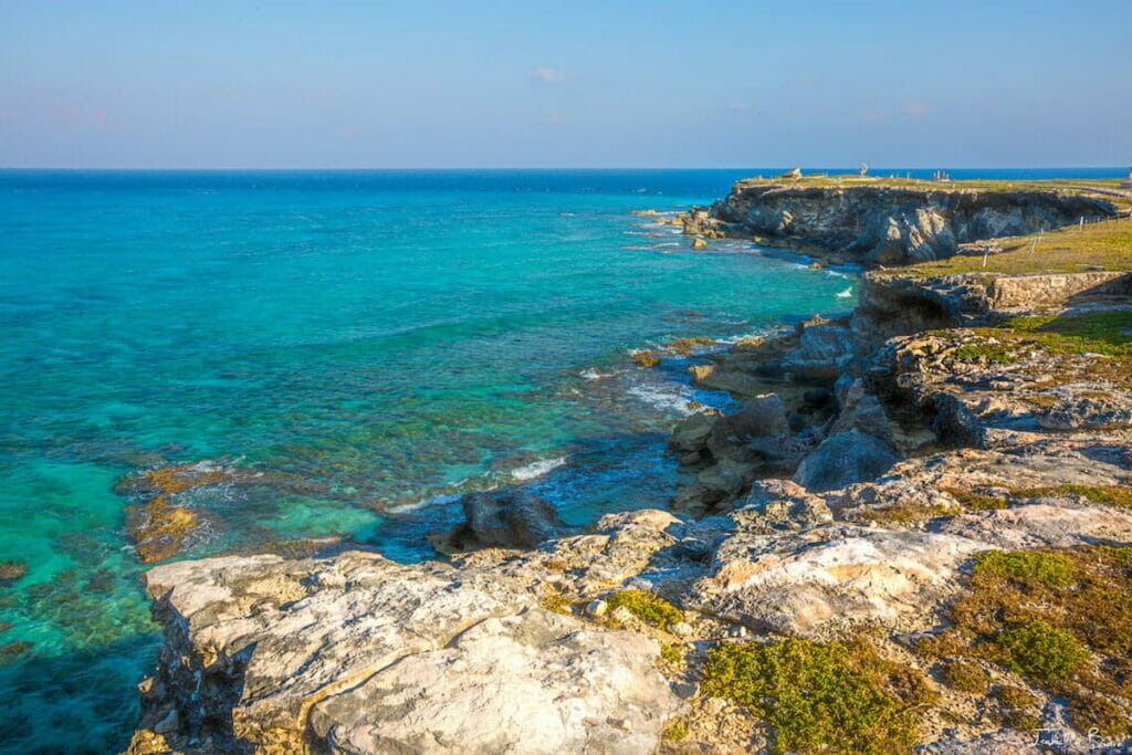Punta Sur's rocky coast and blue beach under a clear sky.