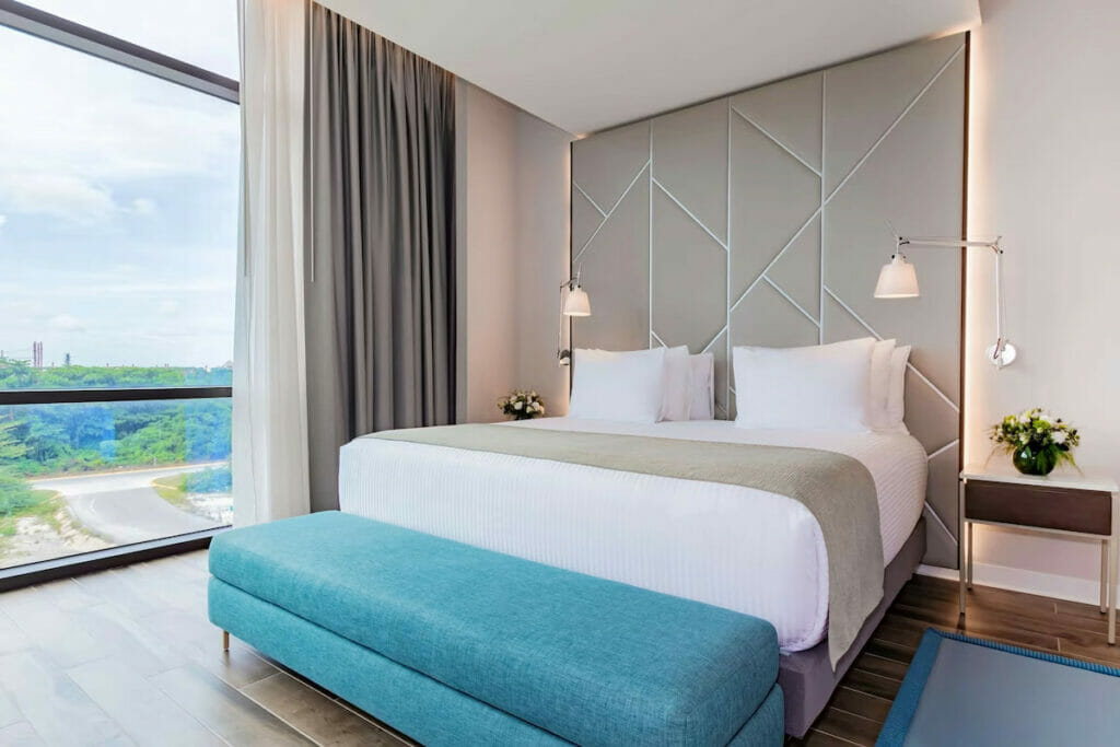 A hotel room with a bed and a ceiling-to-floor window.