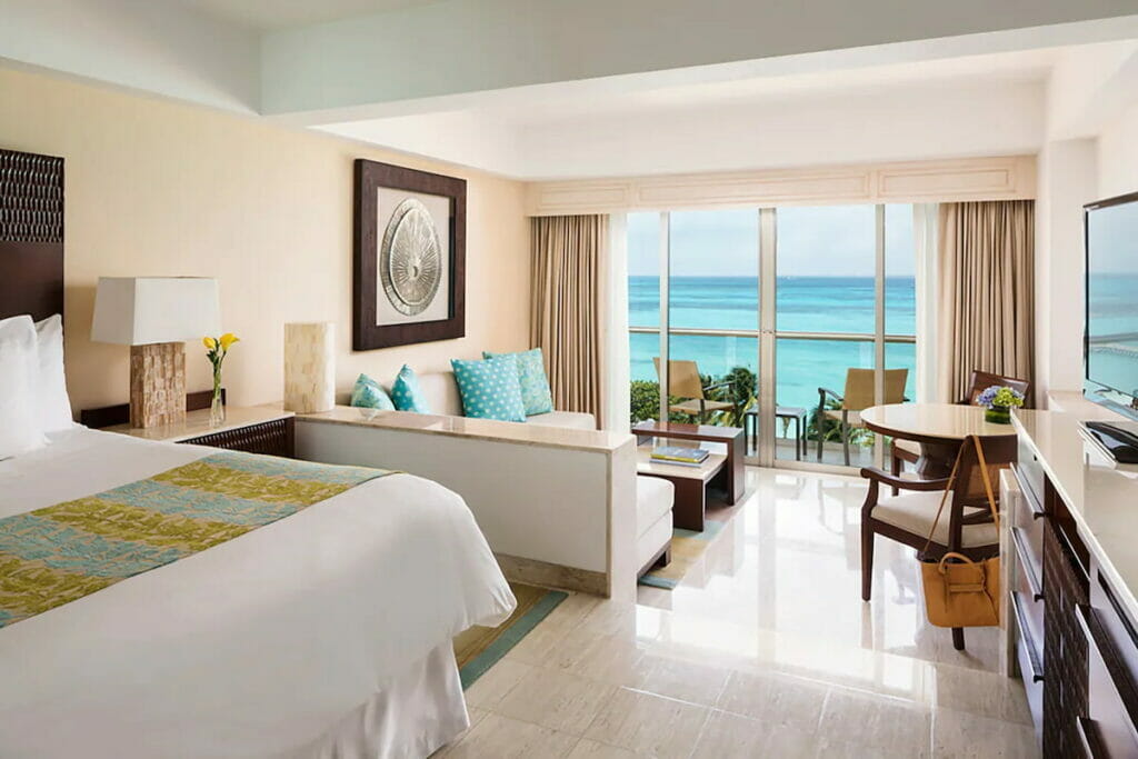 A spacious hotel room with a bed and living room area and balcony.