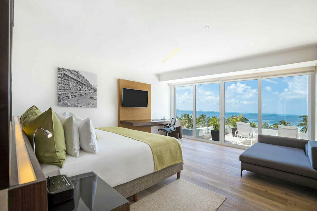 A spacious hotel room with bed, sofa, and a balcony.
