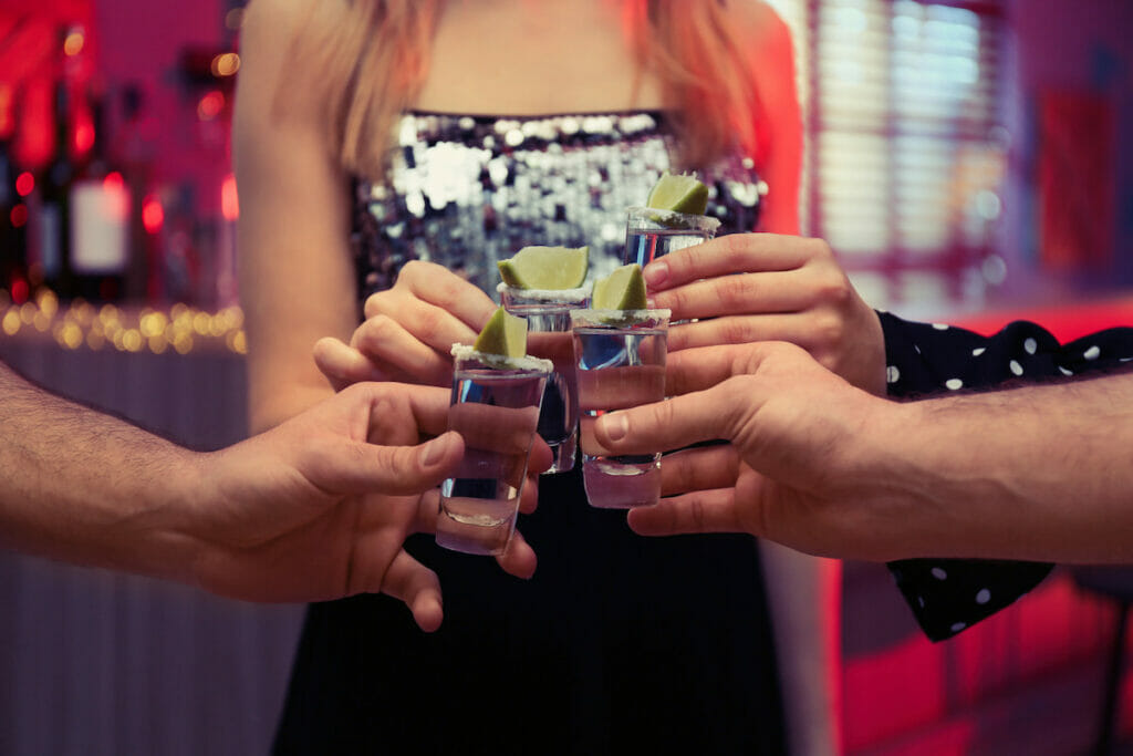 A group of friends holding Mexican tequila shots - a post about drinking age in Cancun.