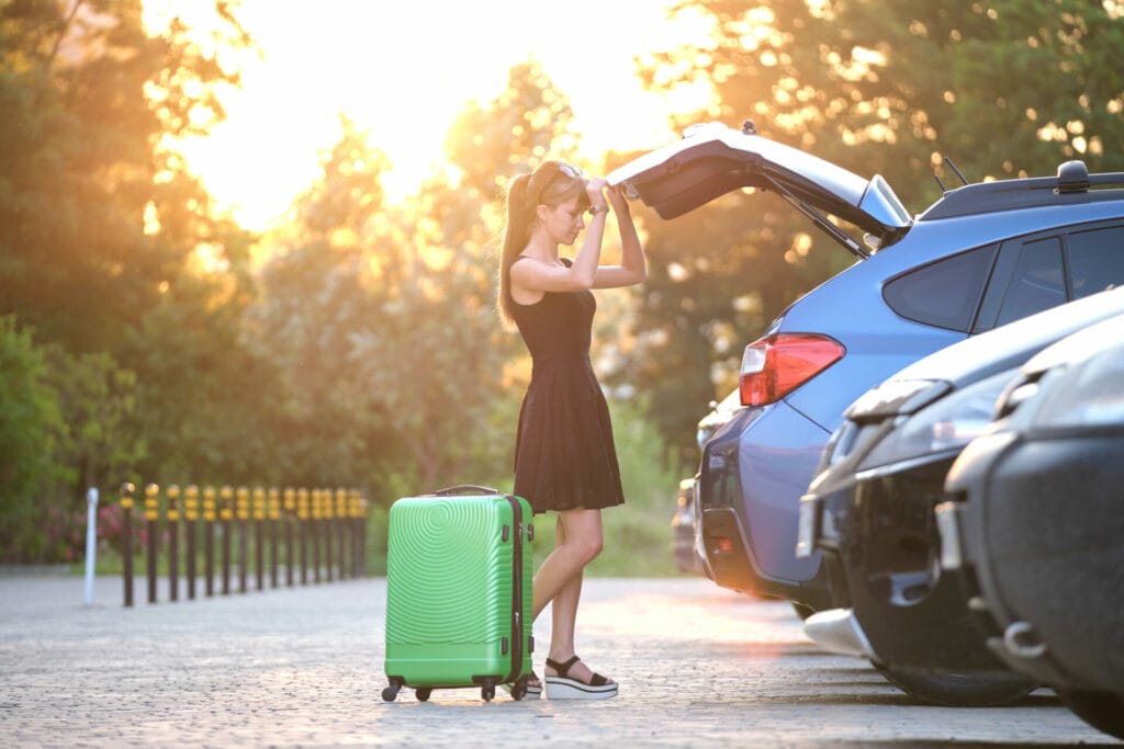 Is renting a car in Cancun Worth It? This Young woman driver is taking out suite case bag of her car.
