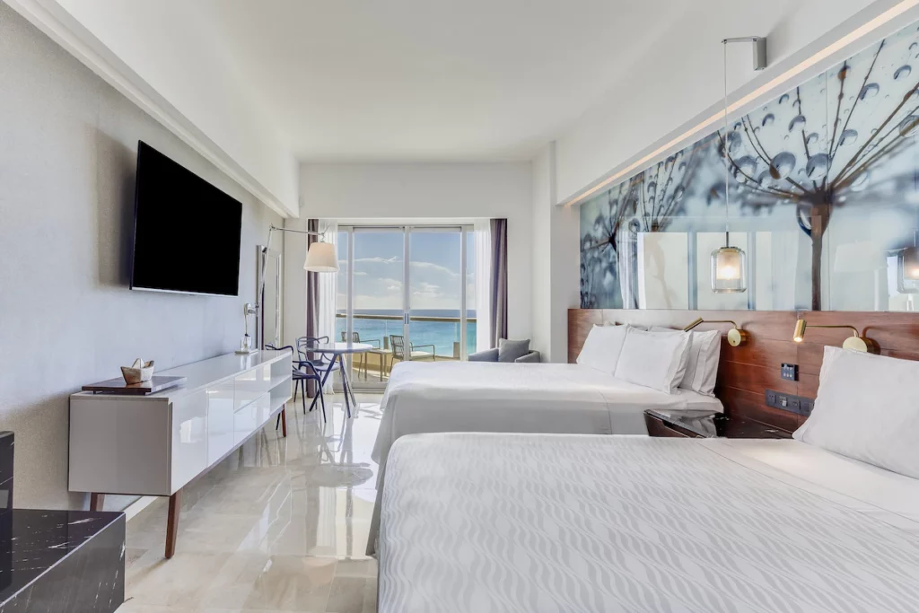 Two queen size beds with white linen and high-class furniture in a hotel in Cancun.