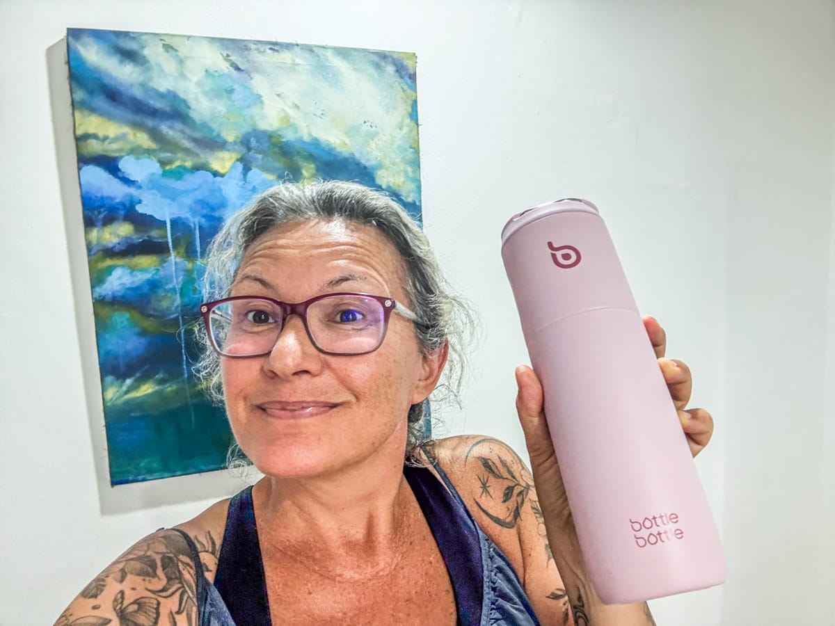 Smiling woman holding a pink bottle.