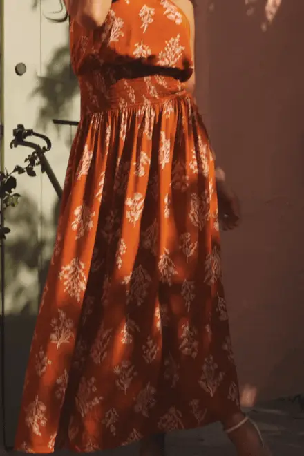 Woman wearing floral orange maxi dress.