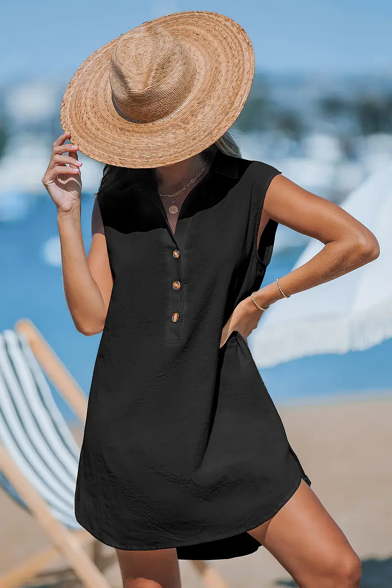 Woman in black dress and straw hat on beach.