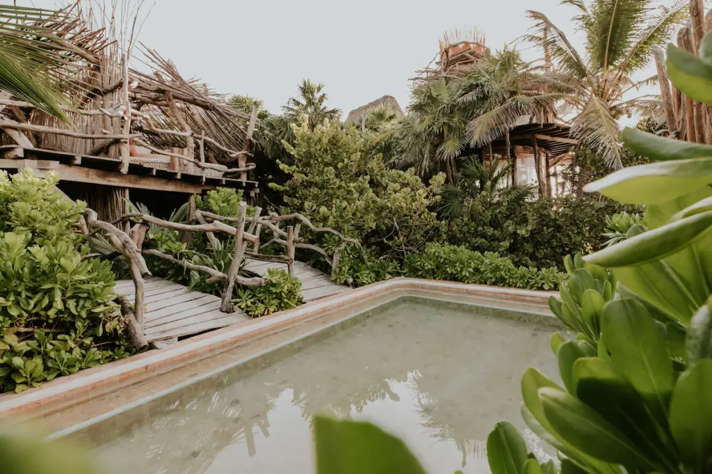 Rustic tropical villa with wooden walkway and lush greenery.